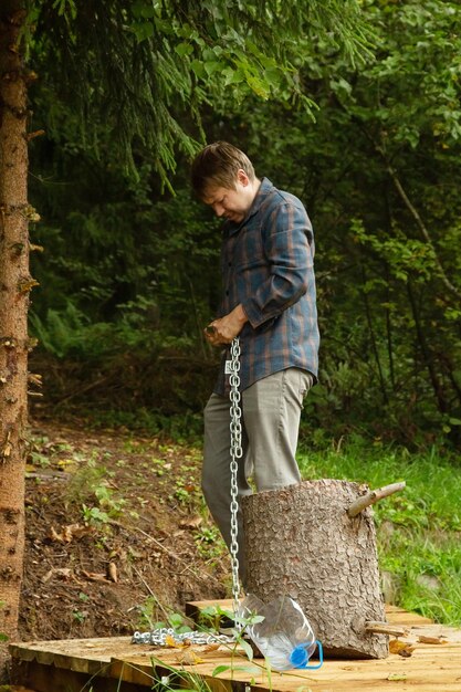 A man pulls a chain while standing on a wooden pier on a forest lake.