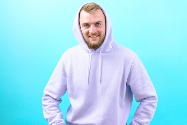 A man in a purple hoodie laughing and looking at the camera on
the blue background face beard healthy hoodie natural front style
good joyful posing individuality relax relaxed teeth