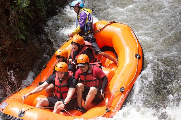 a man in a purple shirt is riding a raft with a life jacket on.