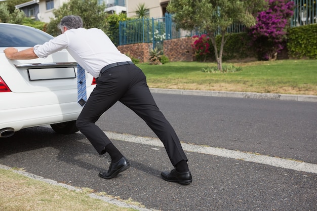 写真 彼の壊れた車を押す男