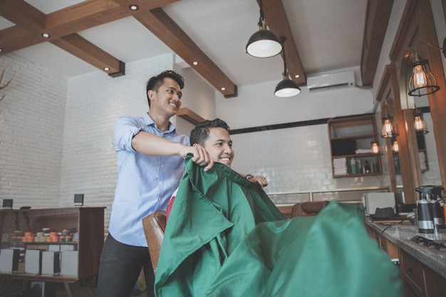 Man put on barber's cape to his client