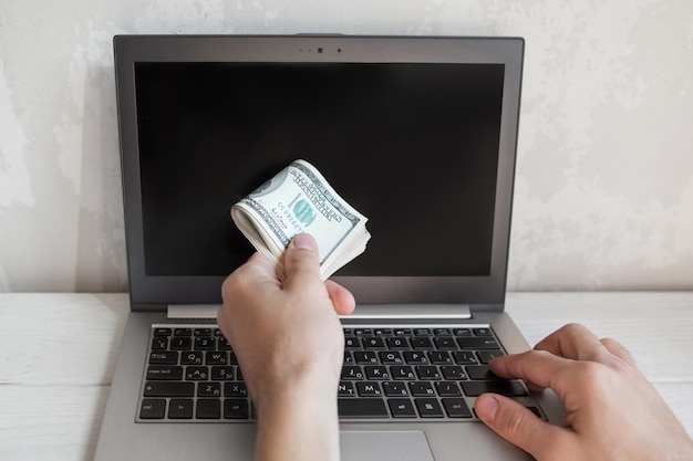 Man put dollars into laptop in giving gesture