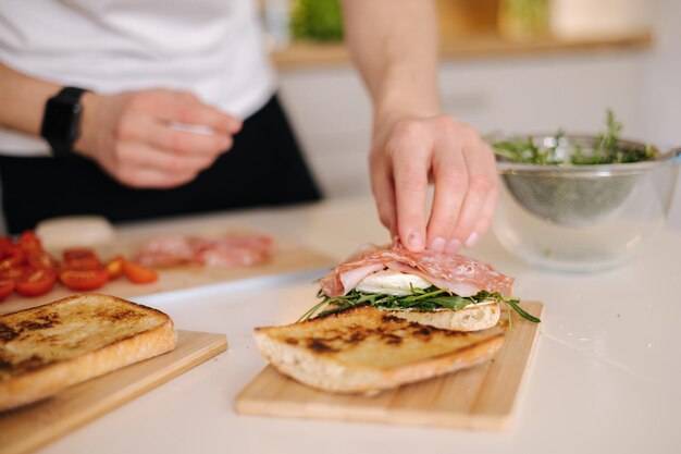 Man put slice of italian salami on top of bruschetta healthy home made food