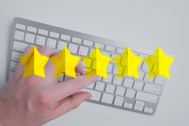 男は白のキーボードを使用してインターネットに5つの星の抽象的な評価を付けます。最高のスコア。平干し。