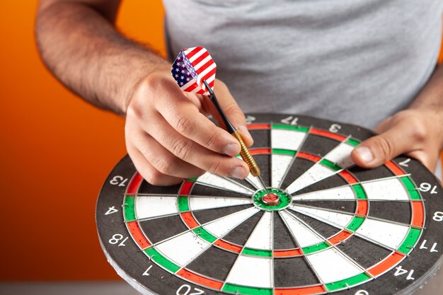 The man puts the dart in the center of the dart board. goal concept