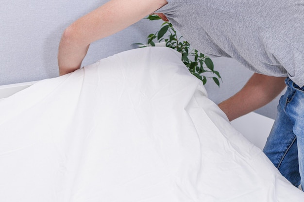 A man puts an elasticated sheet on the mattress change of bed linen