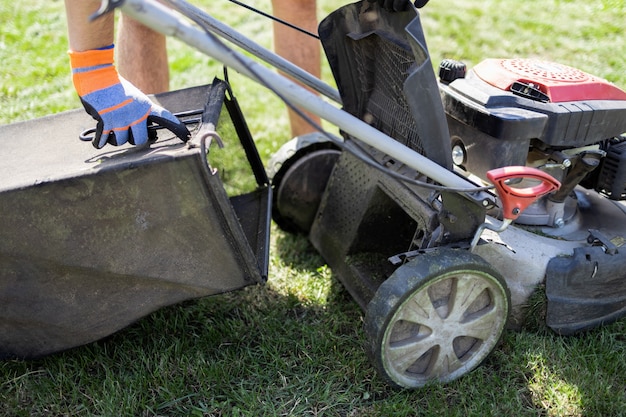 Man puts an empty lawn mower catcher in place