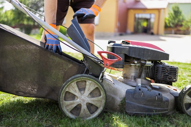 Man puts an empty lawn mower catcher in place