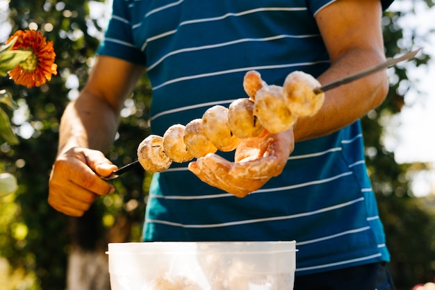 A man puts on a mushroom skewer