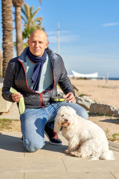 Man puts poop in a bag for his dog in the park.