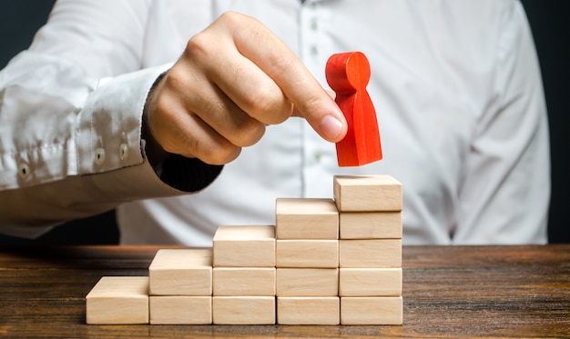 A man puts a red human figure on top of the stairs Career growth improvement of skills