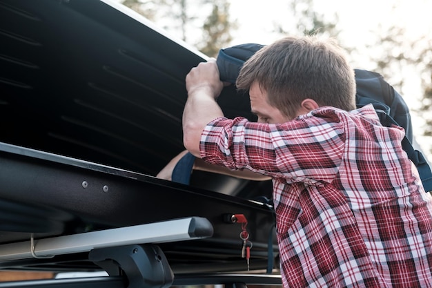 Photo man puts things in the roof rack of a car or in a cargo box