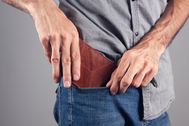 Man puts wallet in front pocket on gray background