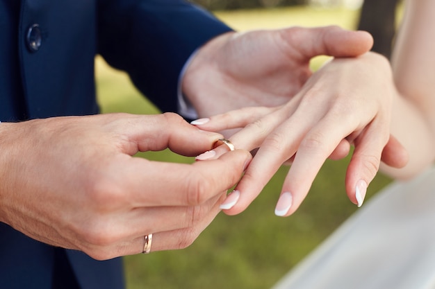 Мужчина надевает обручальное кольцо на палец невесты