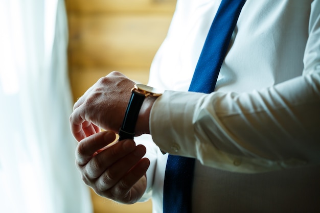 Man puts on a wedding suit and accessories on the wedding day.