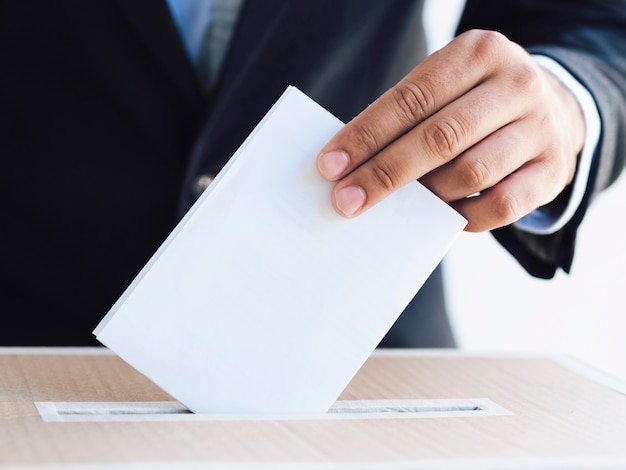 Man putting the ballot in a box close-up