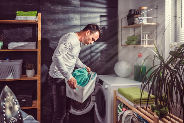 Man putting clothes into washing machine