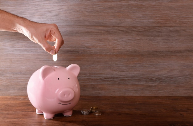 Man putting coin in pig moneybox