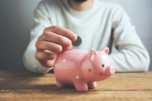 Man putting coin in piggy bank