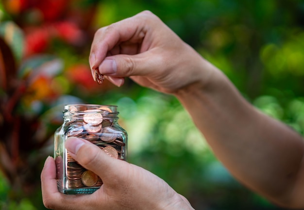 Man putting coins into glass bottle for money