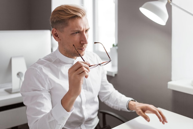 Man putting on glasses in office