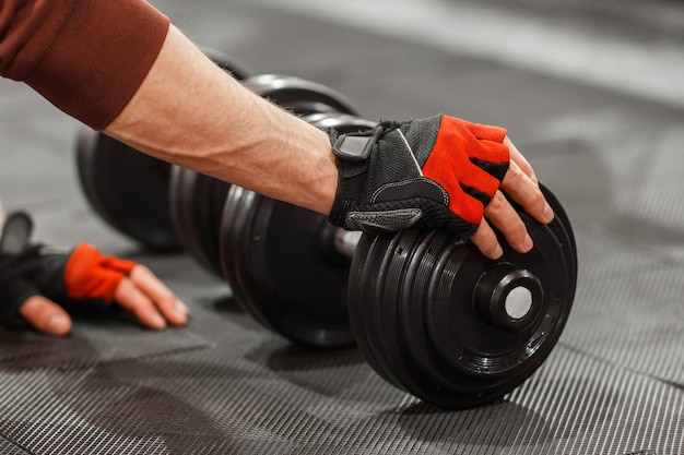 Man putting hand on dumbbell on gym floor