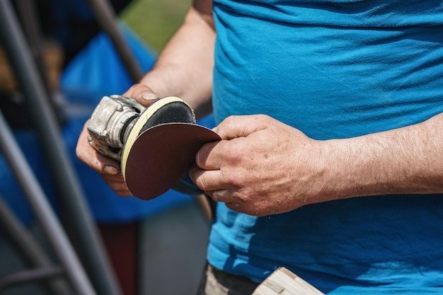 Photo man putting new sandpaper on rotary grinder detail on his hands only