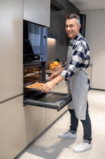 Man putting pan in oven looking at camera