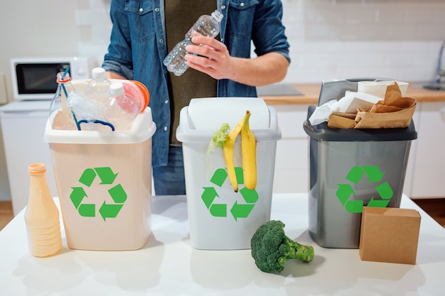 Man putting plastic bottle in the garbage bin in the kitchen