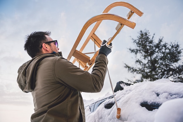 Man putting sled onto car roof