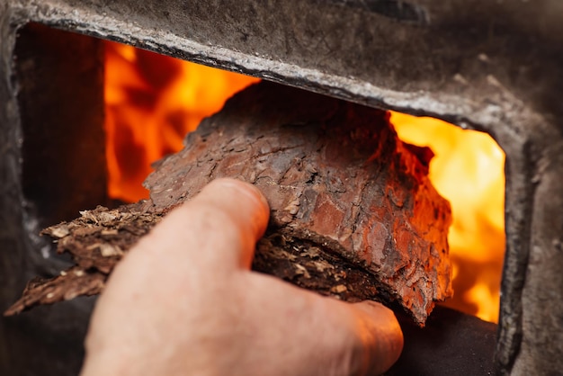 Man putting tree bark in solid fuel boiler Making temperature higher in the heating system of the house defense against cold in winter