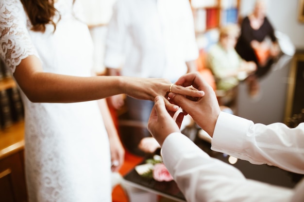 Foto l'uomo mette l'anello di nozze sul dito della donna scambiano gli anelli di nozze sposo e sposa felici