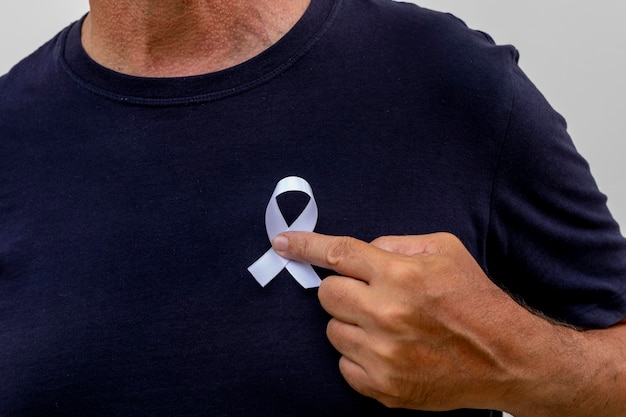 Man putting white ribbon on his shirt. represents a mental health prevention program. January White.