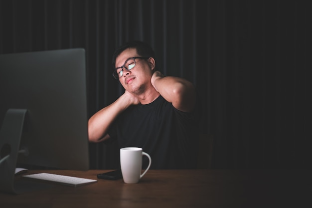 Man raakt zijn nek aan vanwege pijn bij het werken op de computer