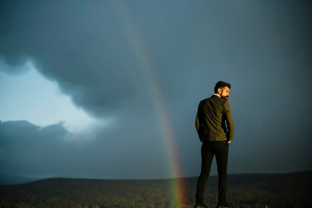 Man and rainbow on grey sky Man with beard and mustache on vacation copy space