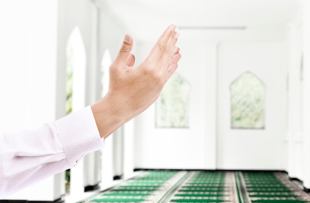 man raised hands and praying in the mosque