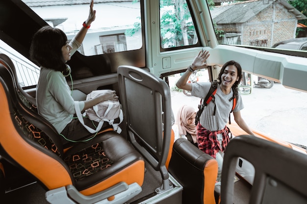 A man raised his hand to greet his friend when he got into the bus