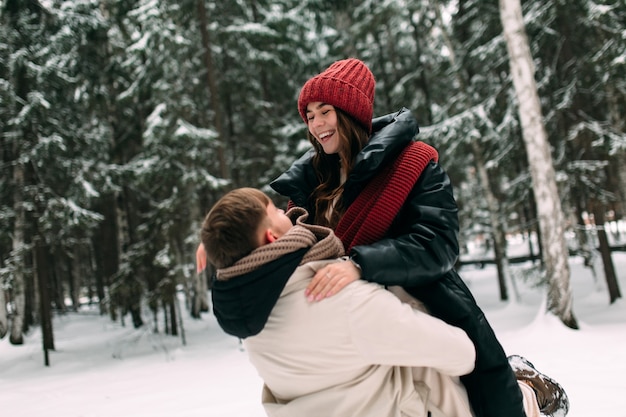 A man raised a woman in his arms in the middle of a snowy forest