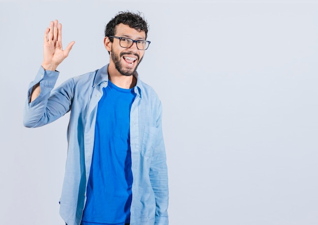 Foto uomo che alza il braccio e sventola un bell'uomo isolato amichevole che dice ciao uomo di faccia amichevole che dice addio concetto di uomo che dice ciao su sfondo isolato