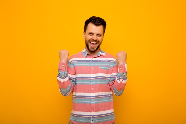 Man raising his fists with smiling delighted face, yes gesture, celebrating success