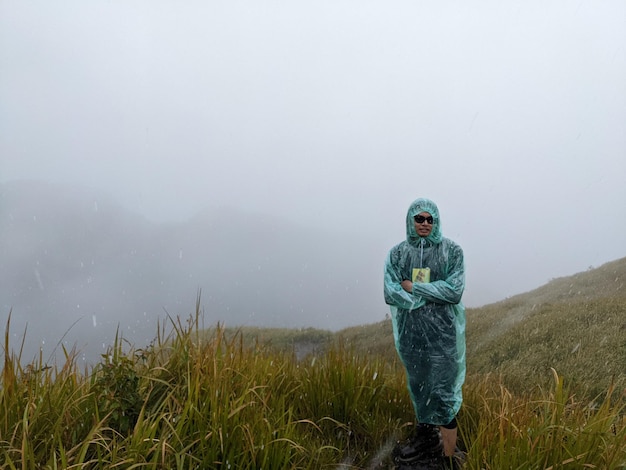 霧のバイブで雨の日に山の頂上に到達する男