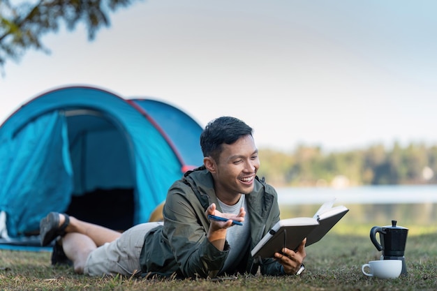 Foto l'uomo legge un libro mentre viaggia con il campeggio il concetto di stile di vita della gente moderna nel lavoro
