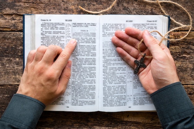 Man reading a bible and holding a cross