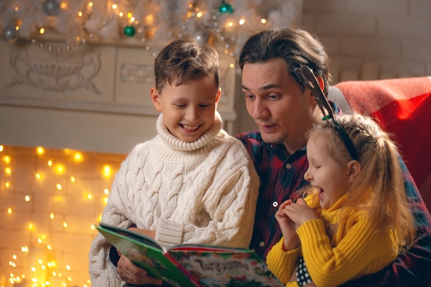 man reading a book to a boy and a girl