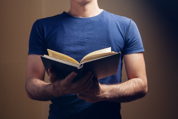 Man reading a book while standing on brown background