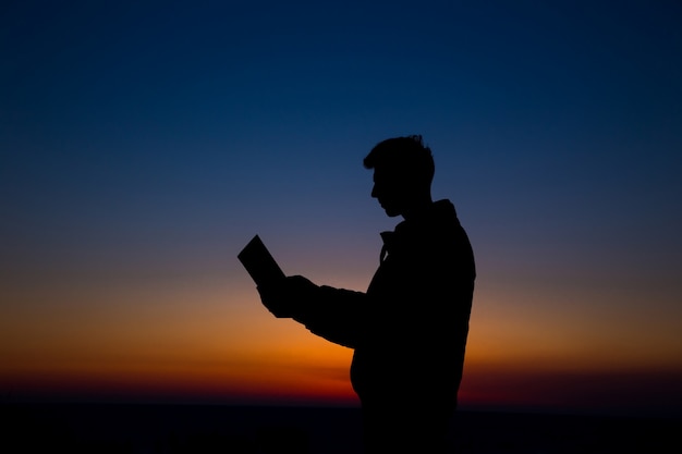 Man reading in the field against sunset