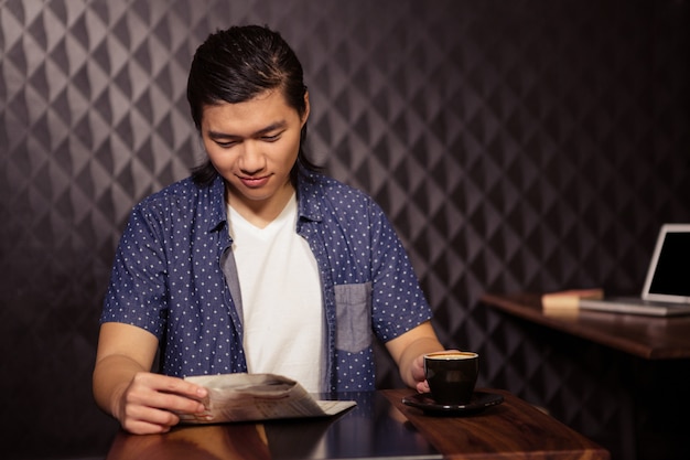 Man reading the newspaper and drinking coffee