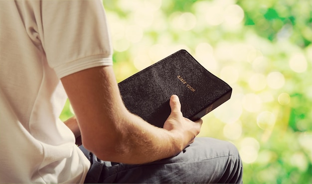 Man reading old Bible book on background