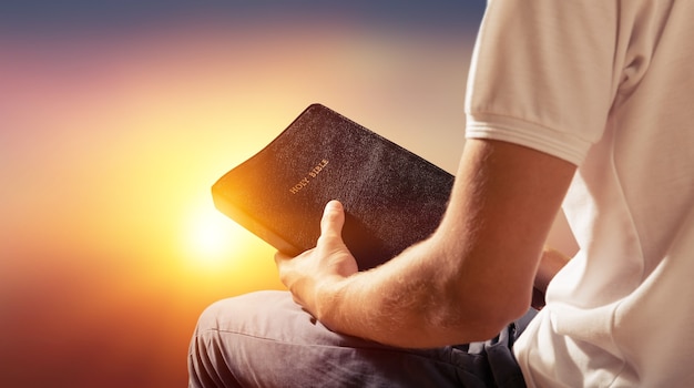 Фото Человек, читающий старую книгу библии на фоне