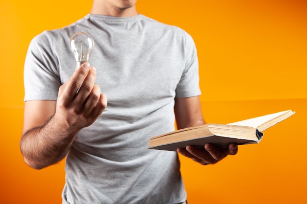 A man reads a book and holds a light bulb. conceptual idea from the book on the orange office